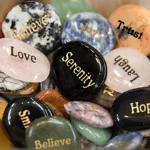 Gemstones in a wooden bowl with words on them - smile, laugh, serenity, Hope, love, trust, believe, joy